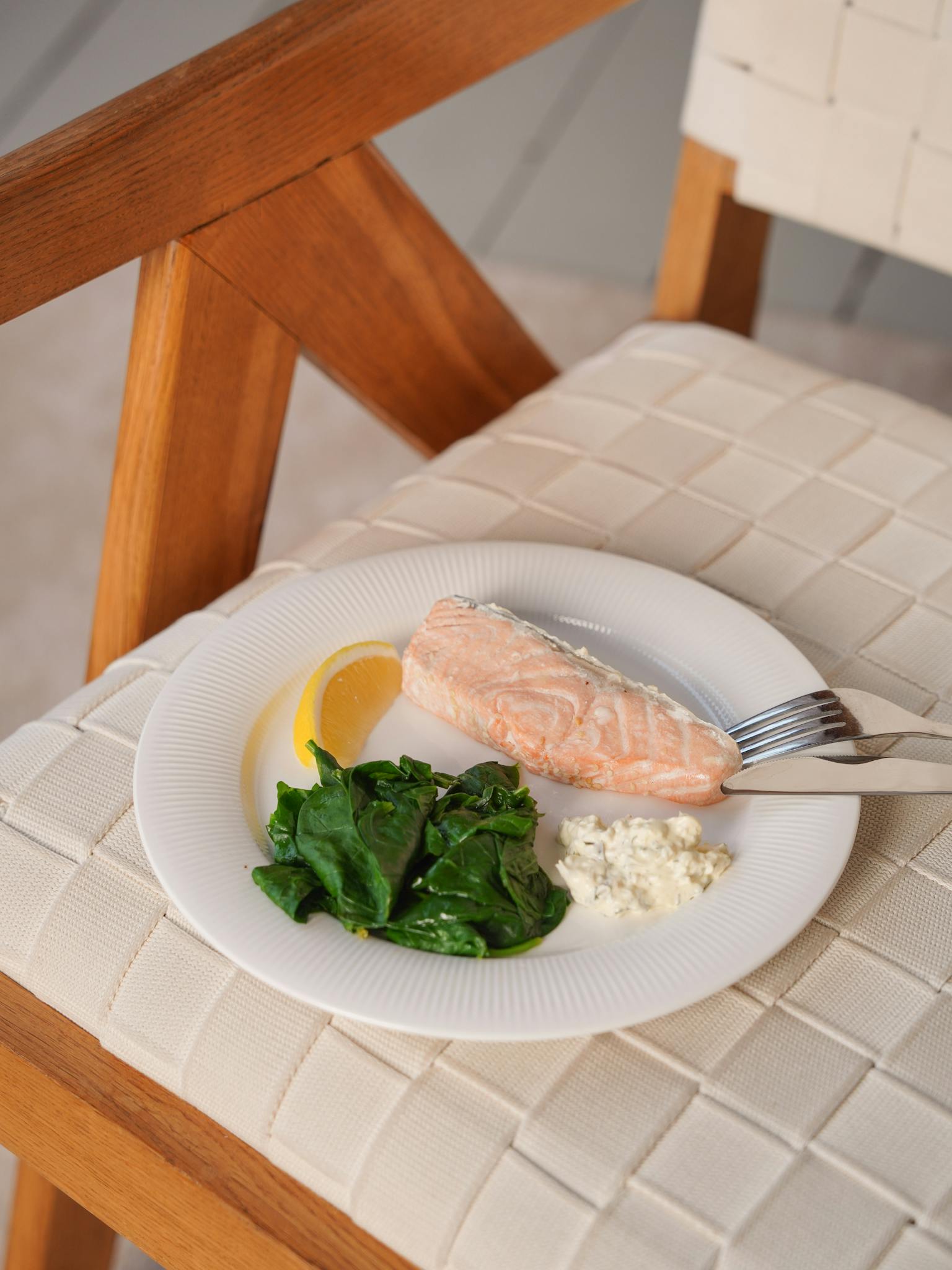 A healthy salmon dish served with spinach and lemon on a chair.